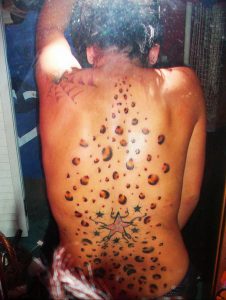 Фото тату леопардовых пятен и звезды на спине. Черно-коричневые пятна, имитирующие шкуру леопарда, и звезда в нижней части татуировки. Оригинальный дизайн.
