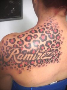Фото тату: татуировка леопардовой шкуры на плече с надписью "Ramirez", выполненная в красно-черных тонах.