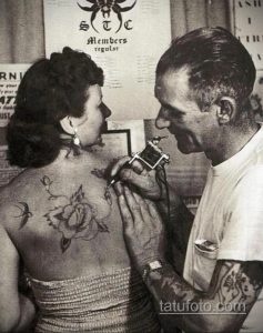 Фотография процесса нанесения татуировки розы на спину девушки. Мастер работает над деталями рисунка.