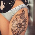 Фото тату на бедре: изящная мандала, выполненная в технике blackwork, с добавлением цветочных элементов. Детализированный рисунок татуировки.