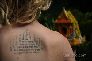 Фото тату демонстрирует традиционную тайскую татуировку (сак янт) на спине мужчины, выполненную черными чернилами в религиозном стиле.