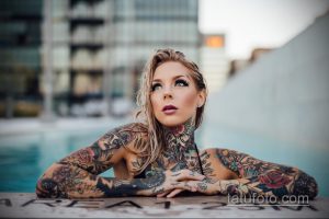 Фото девушки с множеством ярких татуировок на теле, позирующей у бассейна. Рисунки в стиле традиционный и олдскул.
