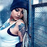 Фото тату на шее и плече девушки с красочным рисунком в стиле традиционной татуировки. Изображены цветы, птицы и другие элементы.