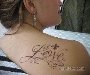 Фото тату с надписью "Love" и изображением флер-де-лис на лопатке. Изящный и романтичный рисунок татуировки.