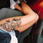 Фото тату черно-белого букета цветов на бедре девушки. Элегантный и женственный рисунок татуировки, выполненный в реалистичном стиле.