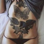 Фото тату на животе с изображением бабочки, двух ласточек и розы. Изображение выполнено в черно-белой гамме, с акцентом на детали и тени.
