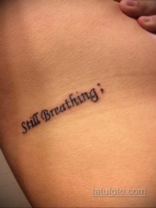 Фото тату: Надпись "Still Breathing;" на теле, выполненная простым шрифтом. Символизирует силу духа и преодоление трудностей.