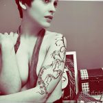 Фотография девушки с татуировкой на руке, представляющей собой портрет и абстрактные элементы. Черно-белое изображение, демонстрирующее детализированный рисунок татуировки.