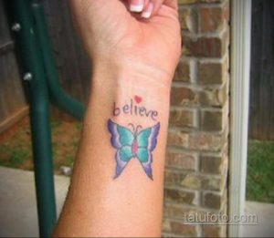 Фото тату: яркая бабочка с надписью 'believe' на запястье. Рисунок татуировки выполнен в акварельном стиле с использованием синих, фиолетовых и розовых оттенков.