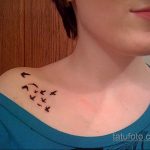 Фото тату на ключице: несколько маленьких черных птиц в полете. Элегантный и минималистичный рисунок татуировки.