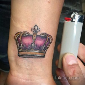 Фото татуировки на запястье: маленькая корона в розовых и фиолетовых тонах. Элегантный и женственный дизайн.