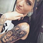 Фото тату: реалистичное изображение льва и короны на руке девушки. Детализированный рисунок в черно-серых тонах, символизирующий силу и власть.
