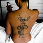 Фото татуировки на спине: феникс в стиле трайбл, выполненный черными линиями. Динамичный и выразительный рисунок татуировки.