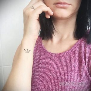 Фото тату: маленькая, минималистичная черная корона на женском запястье. Идеальный эскиз тату для тех, кто ценит простоту и элегантность.
