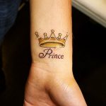 Фото тату на запястье: золотая корона с надписью 'Prince'. Нежный рисунок татуировки для мужчин, выполненный в ярких тонах.