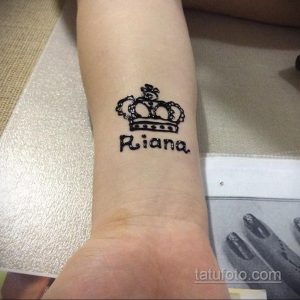 Фото тату: Татуировка короны над именем 'Riana' на женском запястье. Персонализированный и стильный дизайн.