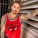 Фото тату на руке мужчины в красной баскетбольной форме Chicago Bulls. Детализированный рисунок на руке, подчеркивающий спортивный образ.