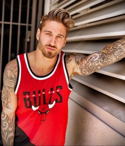 Фото тату на руке мужчины в красной баскетбольной форме Chicago Bulls. Детализированный рисунок на руке, подчеркивающий спортивный образ.