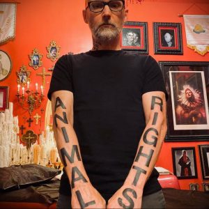 Фото тату надписи 'ANIMAL RIGHTS' на предплечьях мужчины. Черные татуировки, выполненные вертикально вдоль рук, выражают поддержку прав животных.