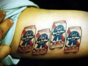 Фото тату на предплечье, изображающее четыре банки пива Pabst Blue Ribbon, выполненное в реалистичном стиле.