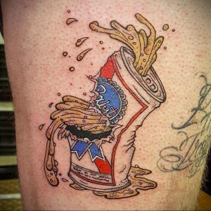 Фото тату на ноге, изображающее банку пива Pabst Blue Ribbon, из которой выливается картофель фри. Яркий и юмористический эскиз.