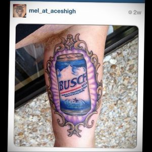 Фото татуировки с изображением банки пива Busch Beer, выполненной в ярких цветах на предплечье. Детализированный рисунок татуировки с реалистичными элементами.