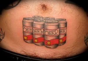 Фото татуировки на животе с изображением шести банок пива с надписью 'BEER' и красными звездами. Рисунок выполнен в стиле традиционной татуировки.