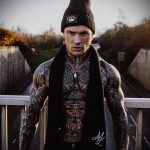 Фото тату на шее и торсе мужчины, выполненное в стиле blackwork с использованием плотных черных линий и геометрических узоров. Подходит для поиска идей для темных и графичных тату.