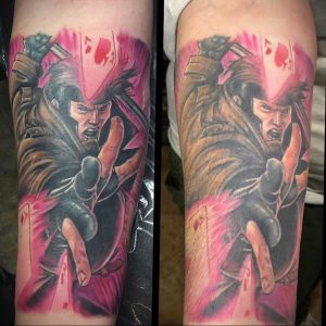 Фото тату на предплечье с изображением Росомахи из комиксов X-Men. Динамичная поза, яркие цвета и брызги краски.