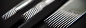 Крупный план трех тату-игл на черном фоне. Иглы предназначены для различных техник татуировки, обеспечивая высокую детализацию и качество рисунка.