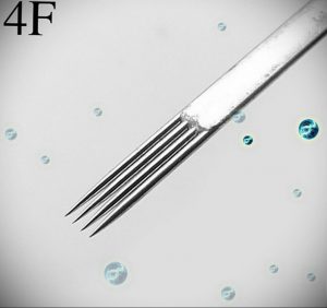 Крупный план стерильной иглы для татуировки 4F. Серебристая игла на светло-сером фоне, окруженная маленькими голубыми кристаллами.