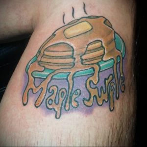 Фото тату с изображением блинчиков и надписи "Maple Swirl" на руке. Оригинальный рисунок татуировки в ярких тонах.
