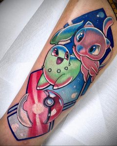 Фото тату Litten и Rowlet на предплечье. Покемоны Litten и Rowlet в покеболе на фоне звездного неба. Красочный рисунок татуировки в стиле аниме.