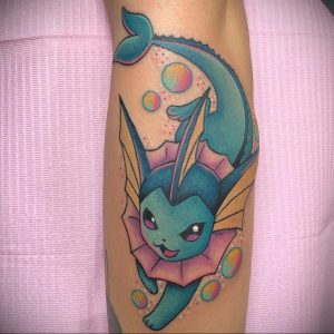 Фото тату Vaporeon на предплечье. Синий покемон Vaporeon с плавниками и пузырьками. Красочный рисунок татуировки в стиле аниме.