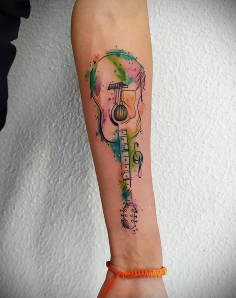 Цветная акварельная тату с гитарой на предплечье девушки - фото