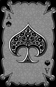 Фото тату: карта Ace of Spades с замысловатым орнаментом внутри, выполненная в черно-серой гамме на фоне узора.