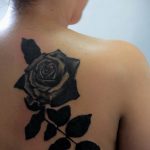 Фото татуировки черной розы на спине. Изящный рисунок татуировки с детально проработанными лепестками и листьями. Идеальный эскиз тату для женщин.