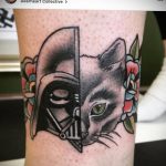 Фото тату, сочетающего в себе Дарта Вейдера и кота на руке, выполненное в стиле традиционной татуировки с яркими цветами.