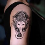 Фото тату бога Ганеши на плече. Черно-белый рисунок в стиле blackwork с высокой детализацией и использованием точечной техники.