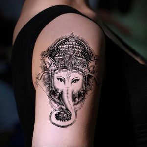 Фото тату бога Ганеши на плече. Черно-белый рисунок в стиле blackwork с высокой детализацией и использованием точечной техники.