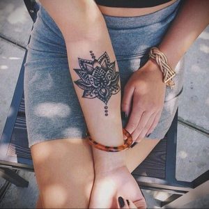 Фото тату мандалы на запястье, выполненное в черном цвете. Простой и элегантный рисунок татуировки с тонкими линиями и геометрическими узорами.