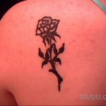 Фото тату: классическая черная татуировка розы с листьями, расположенная на плече. Элегантный и детализированный рисунок татуировки.