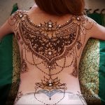 Фото тату хной на спине девушки, сложный восточный орнамент с использованием страз, детальная проработка узора, вдохновение восточными мотивами.