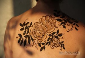Фото тату с изображением пышных пионов на плече. Рисунок выполнен в технике хной, с использованием коричневых оттенков. Идеально для любителей цветочных мотивов.