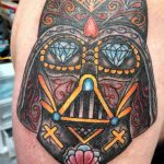 Фото тату Дарта Вейдера, стилизованного под Sugar Skull, на плече. Цветная татуировка с использованием ярких оттенков и сложных узоров.