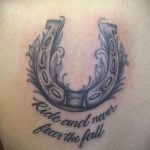 Фото тату подковы с крыльями и надписью 'Ride and never fear the fall' на боку. Мотивационный рисунок татуировки в стиле графика.