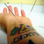 Фото татуировки подковы и четырехлистного клевера с надписью 'LUCKY'. Рисунок выполнен в ярких цветах. Расположение на запястье.
