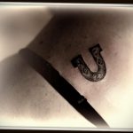 Фото татуировки подковы, выполненной в стиле blackwork. Рисунок выполнен полностью черным цветом с использованием плотных штрихов. Расположение на коже.