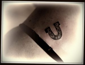 Фото татуировки подковы, выполненной в стиле blackwork. Рисунок выполнен полностью черным цветом с использованием плотных штрихов. Расположение на коже.