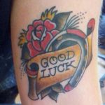Фото тату подковы с розой и надписью "GOOD LUCK" в стиле олдскул. Яркие цвета и четкие линии.